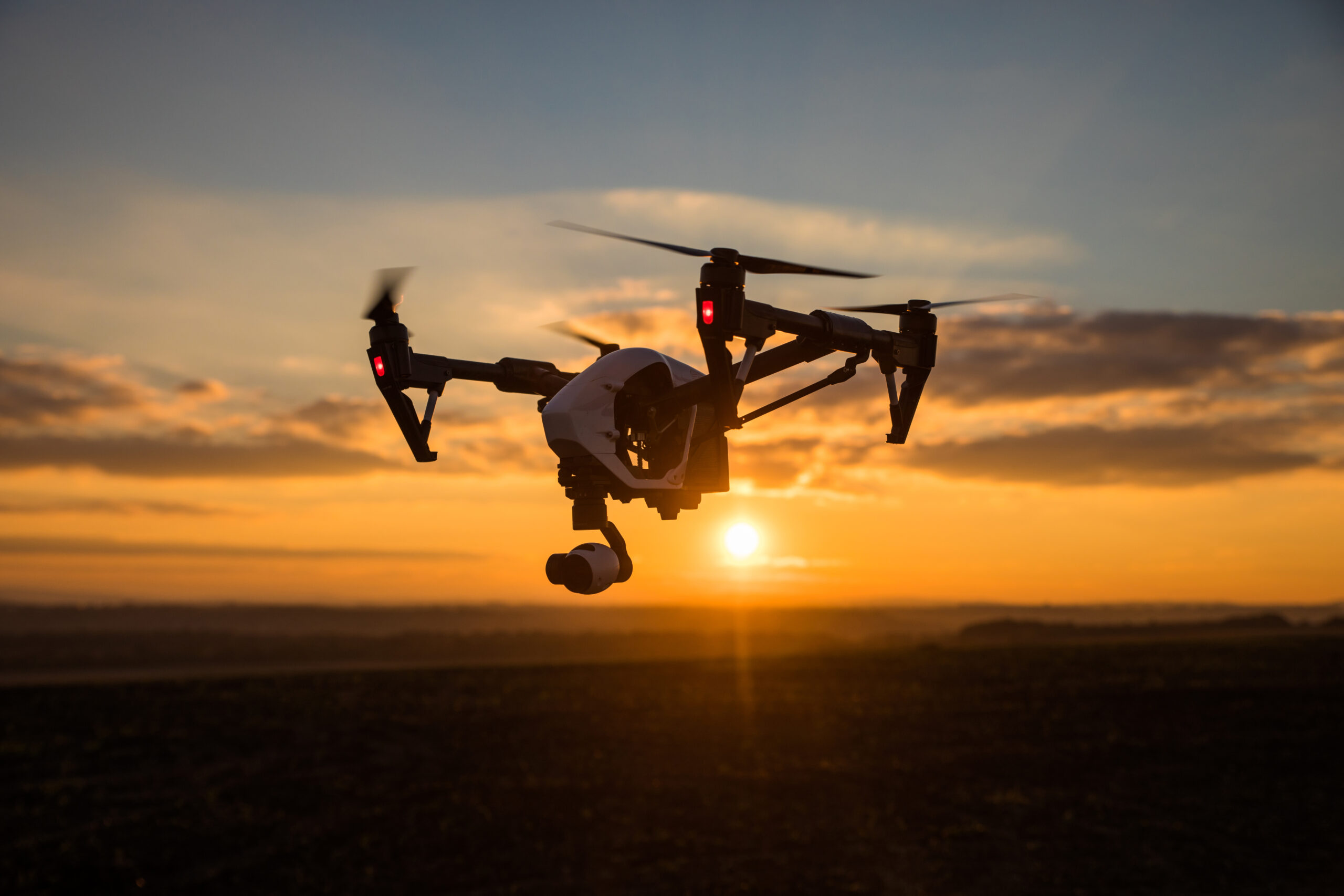 Secteur d'activité : L'aéronotique Tous les moteurs distribués par SMH qui sont utilisés dans l'aéronotique : ÉQUIPEMENTS HÉLICOPTÈRES, moteurs de drones… Drone blanc avec caméra numérique volant dans le ciel au-dessus d'un champ au coucher du soleil