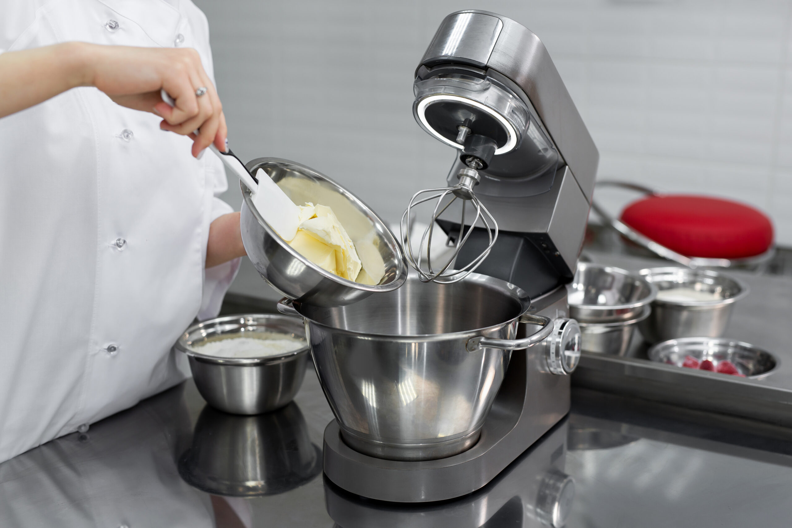 Secteur d'activité : tous les bien de consommation utilisant les moteurs de la Société SMH Motors : Aspirateurs, mixeurs, machine à laver, caméscopes, appareil photo, imprimante, téléphone mobile. Robot culinaire type "cooking chef" sur une table en inox, avec une pâtissière qui ajoute du beurre dans la cuve.